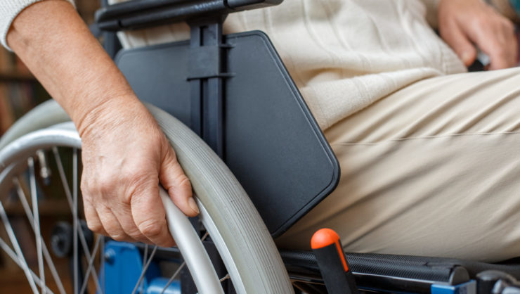 Aged woman with disability recovery at home sitting in a wheelchair moving wheels